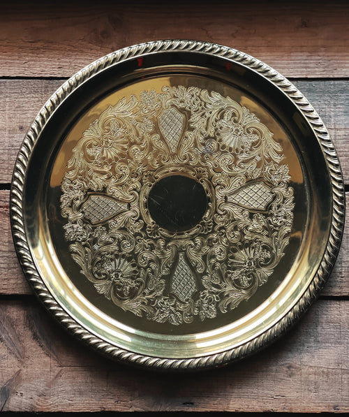 Decorative brass tray with intricate patterns on a wooden surface