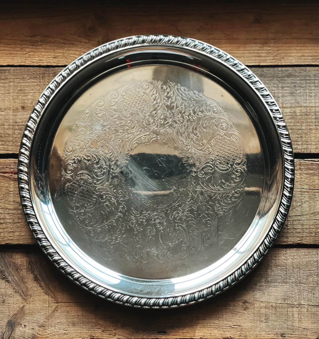Silver tray with intricate designs on a wooden surface