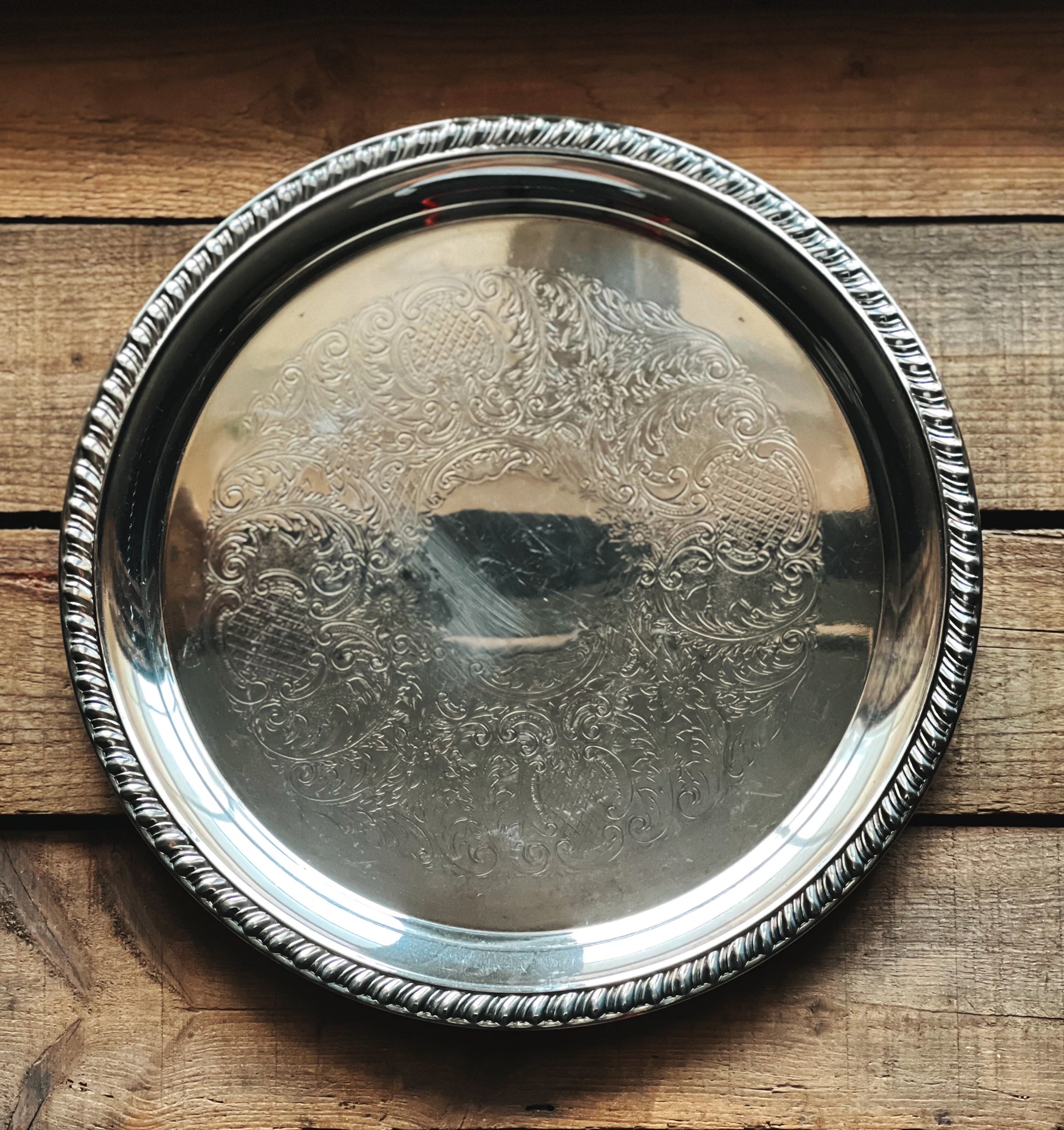 Silver tray with intricate designs on a wooden surface