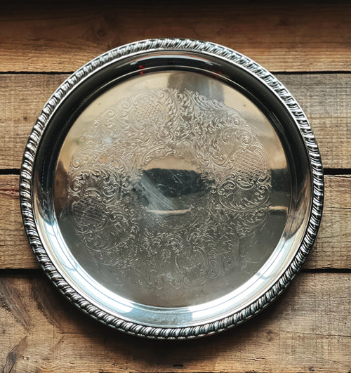 Silver tray with intricate designs on a wooden surface