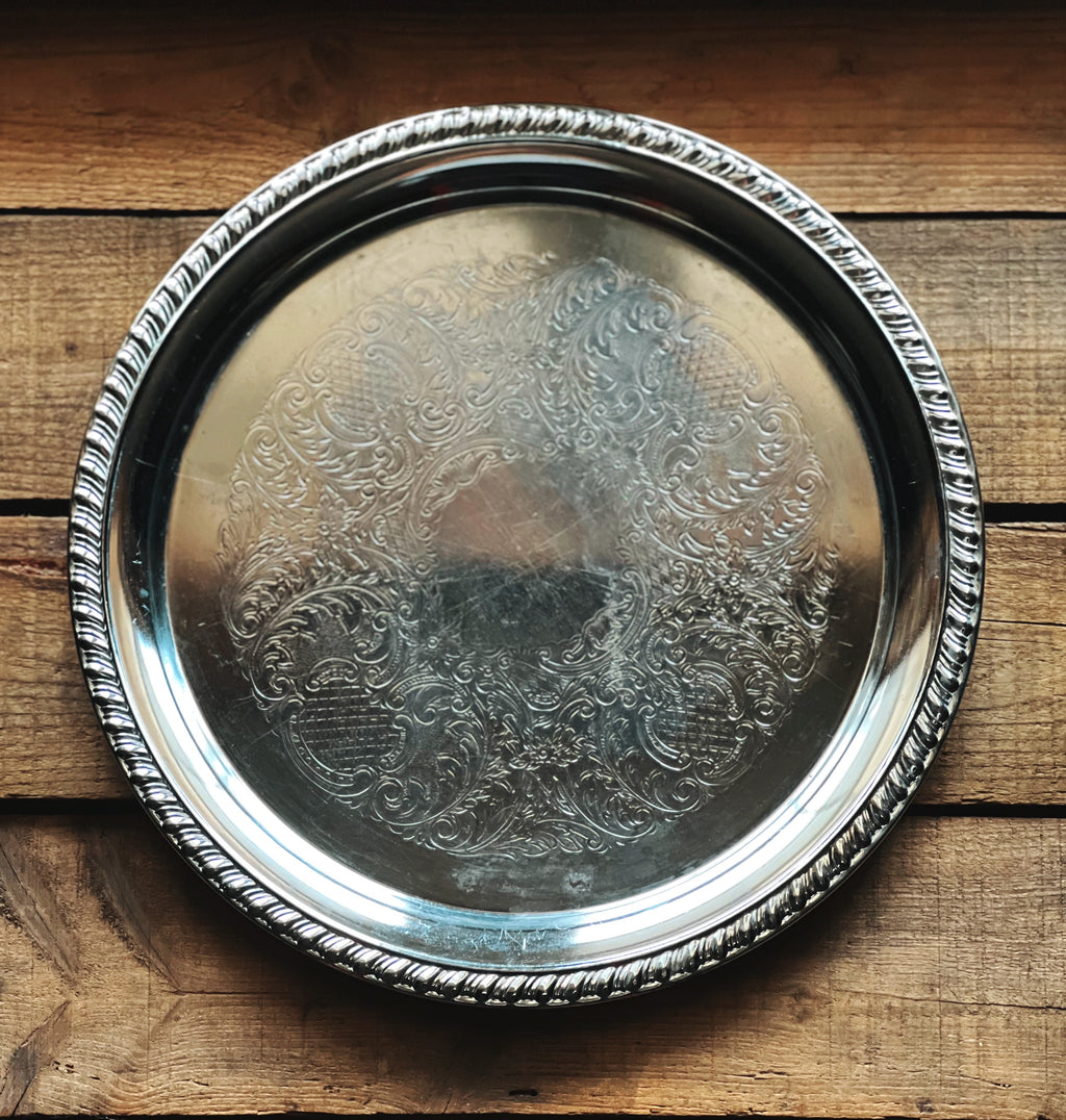 Silver tray with intricate designs on a wooden surface