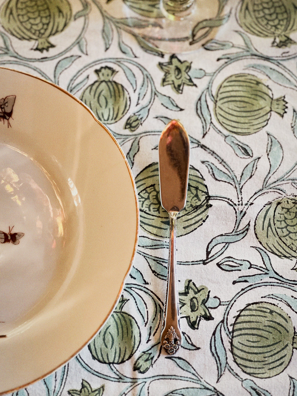 Silver spoon on a patterned tablecloth with a plate in the foreground