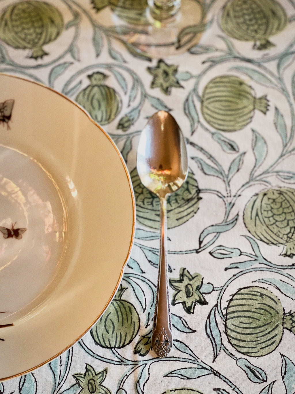Table setting with a decorative tablecloth, plate, and spoon.