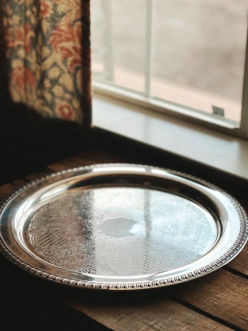 Silver tray on a wooden surface with a window in the background