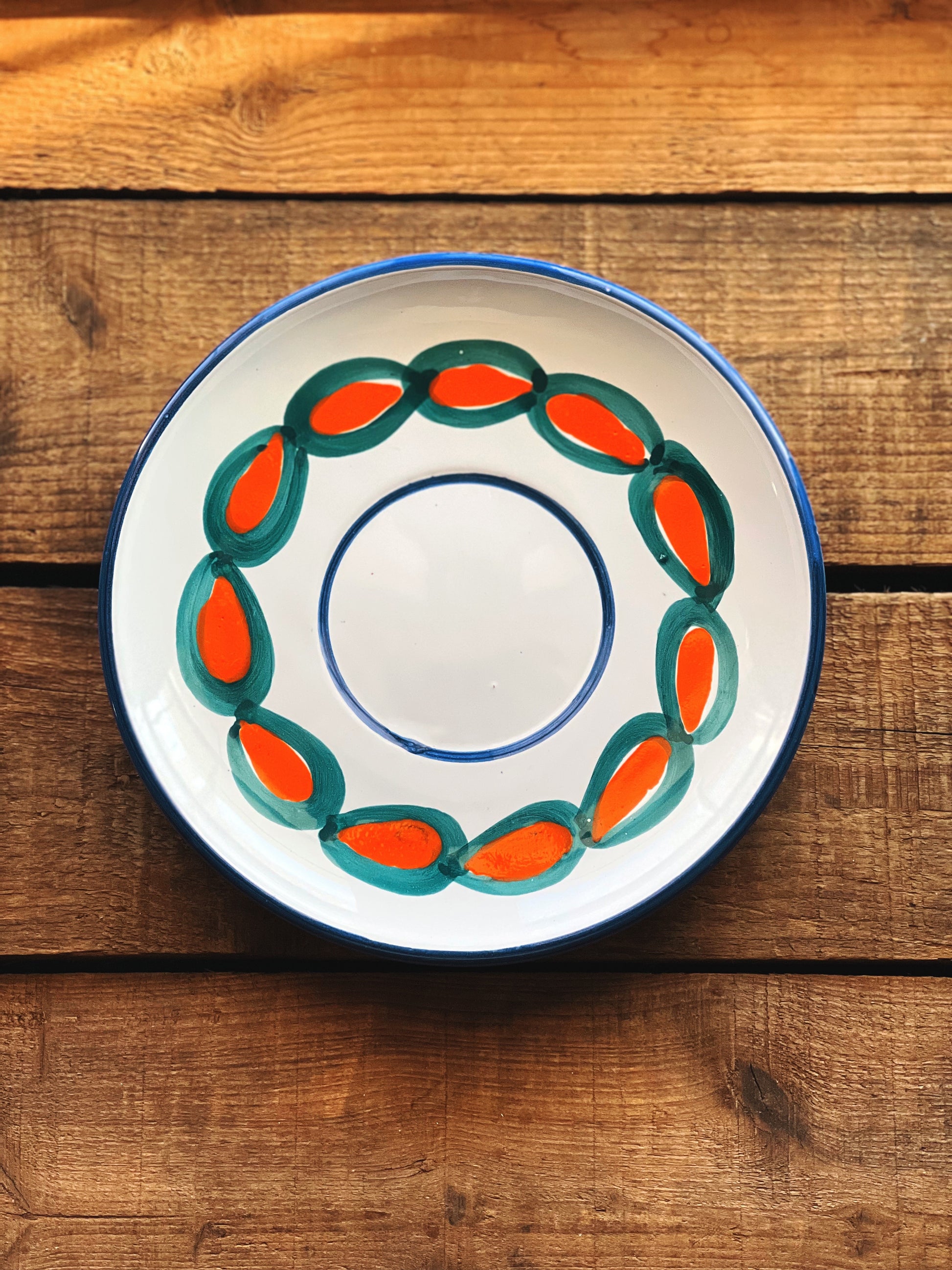 Decorative ceramic bowl with orange and green design on a wooden surface