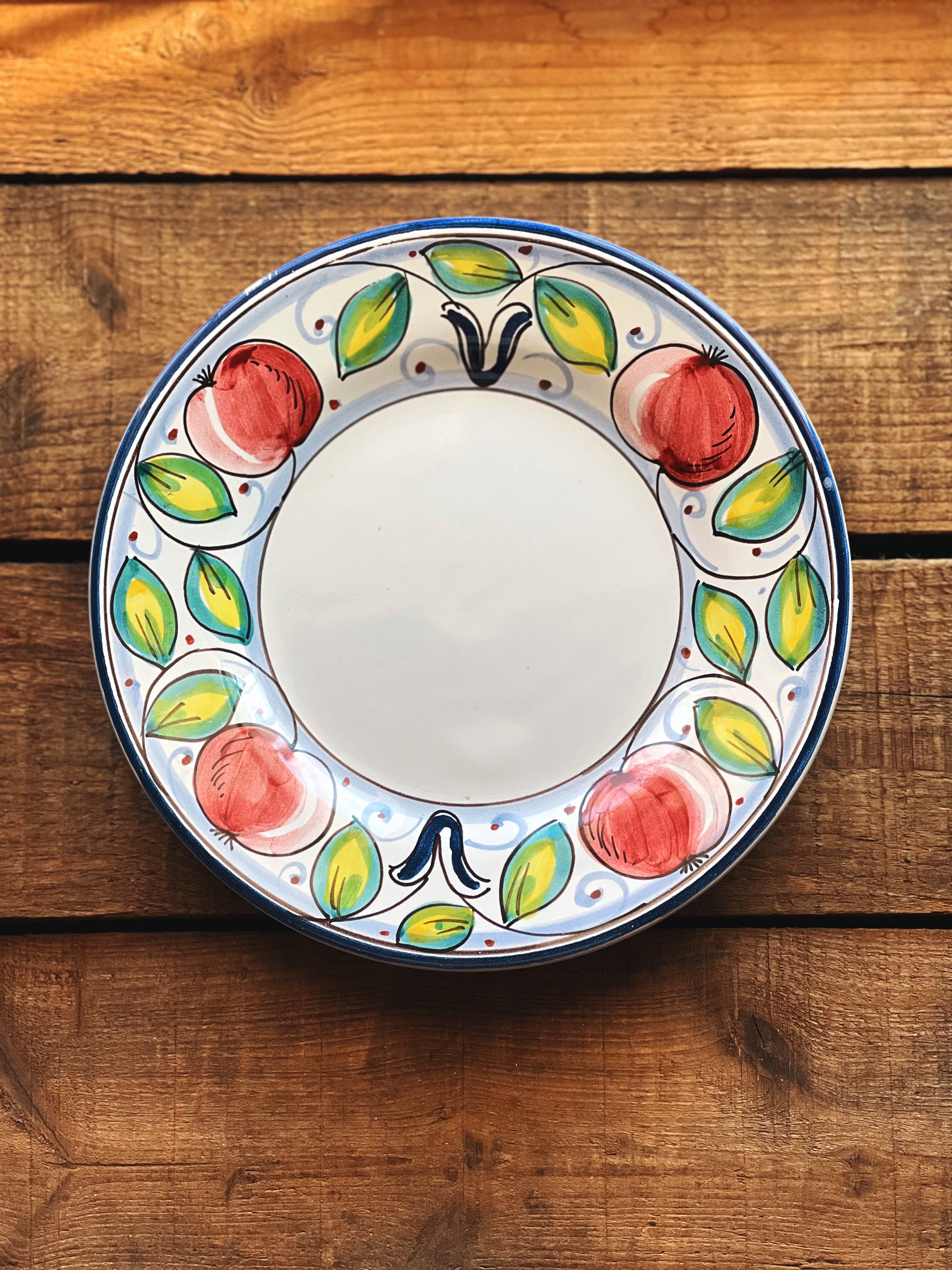 Decorative ceramic plate with fruit design on a wooden surface