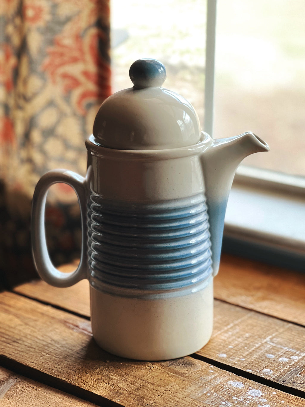 Ceramic teapot with blue accents on a wooden surface