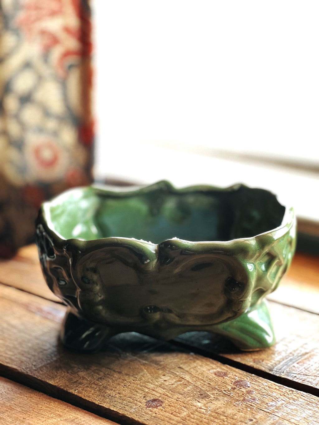Green ceramic bowl on a wooden surface with a blurred background