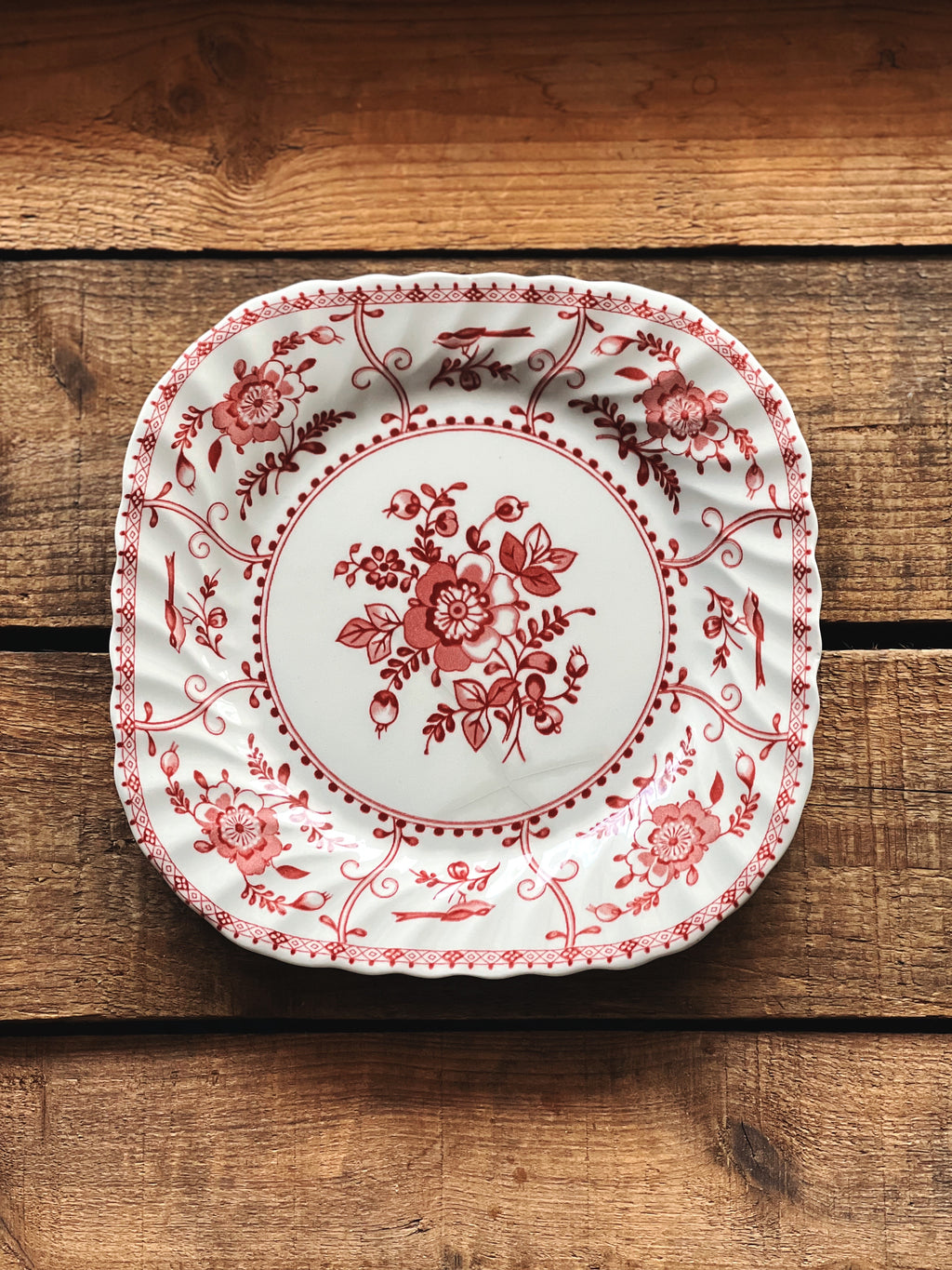 Decorative plate with red floral pattern on a wooden surface