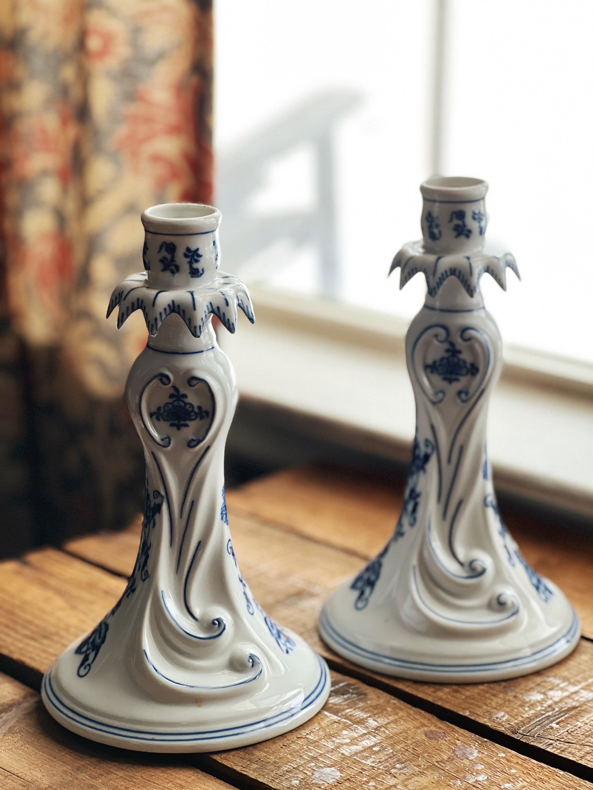 Two ceramic candle holders with blue floral patterns on a wooden surface.