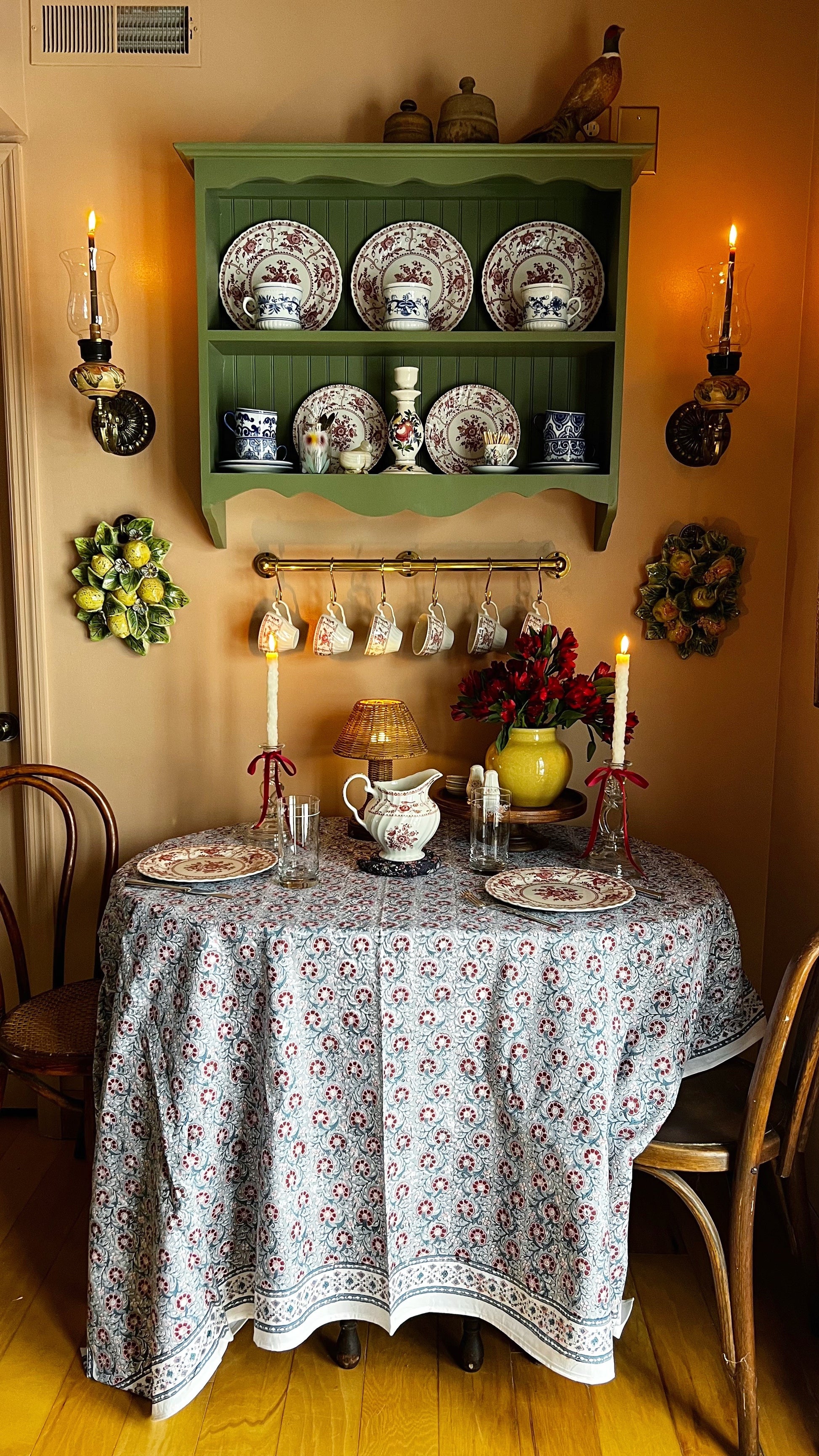 Dining room with a table set for a meal, green wall shelf with plates, and decorative elements.