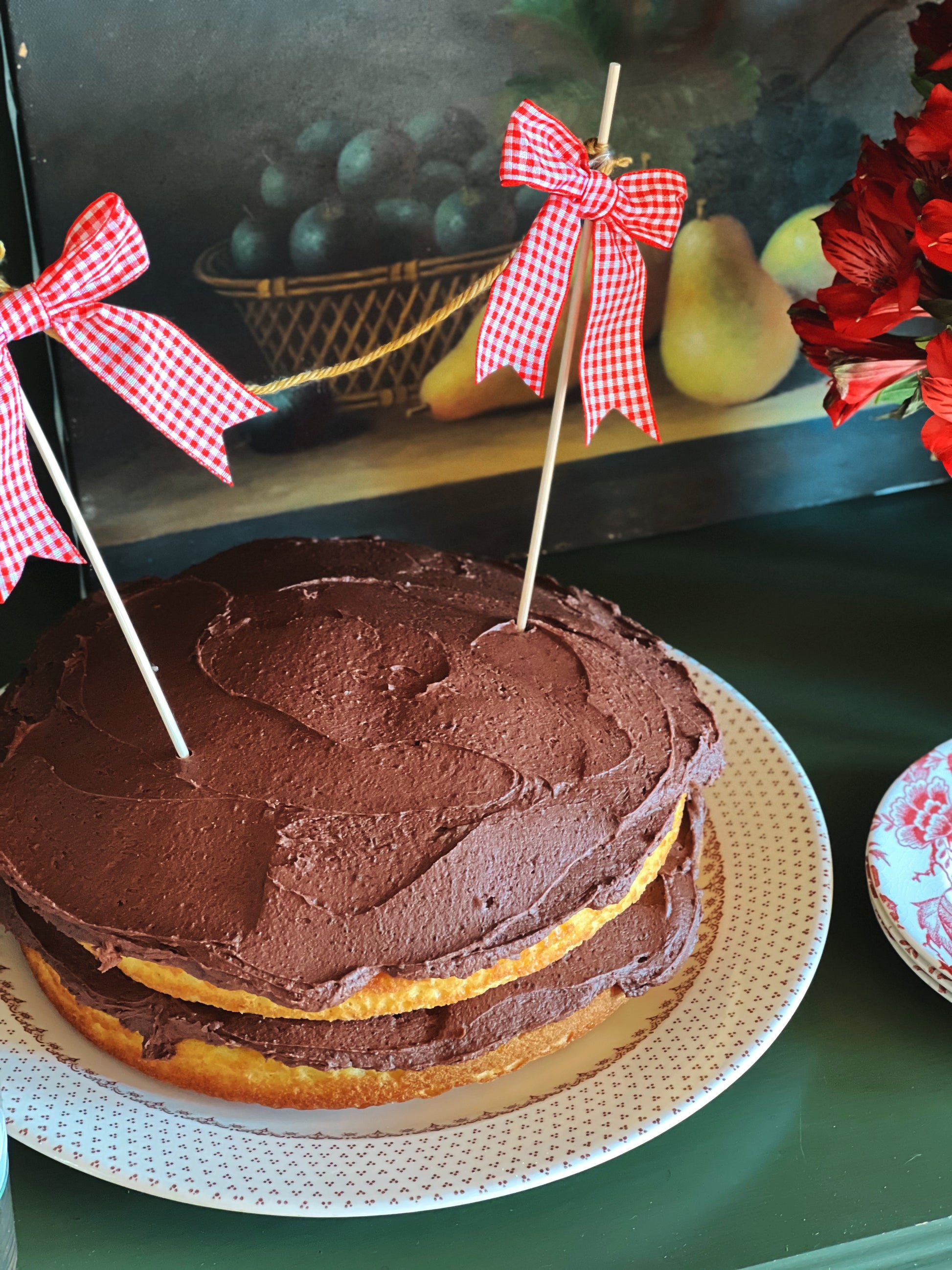 Chocolate frosted cake with red checkered bows on a green table