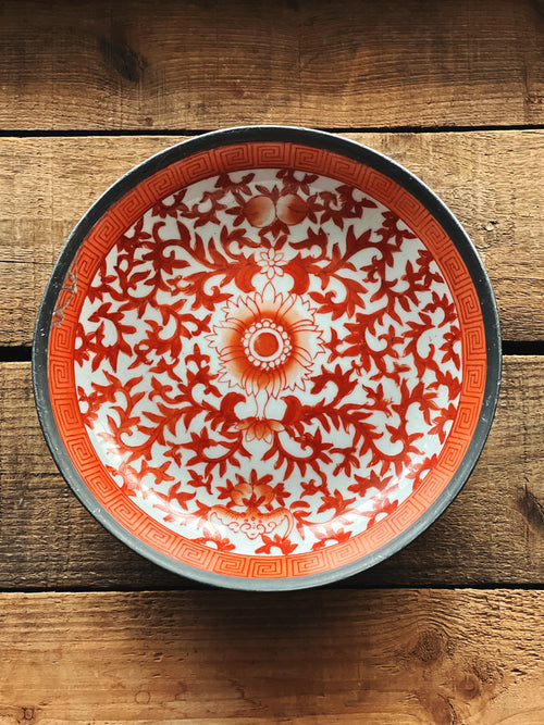 Decorative plate with red and white pattern on a wooden surface