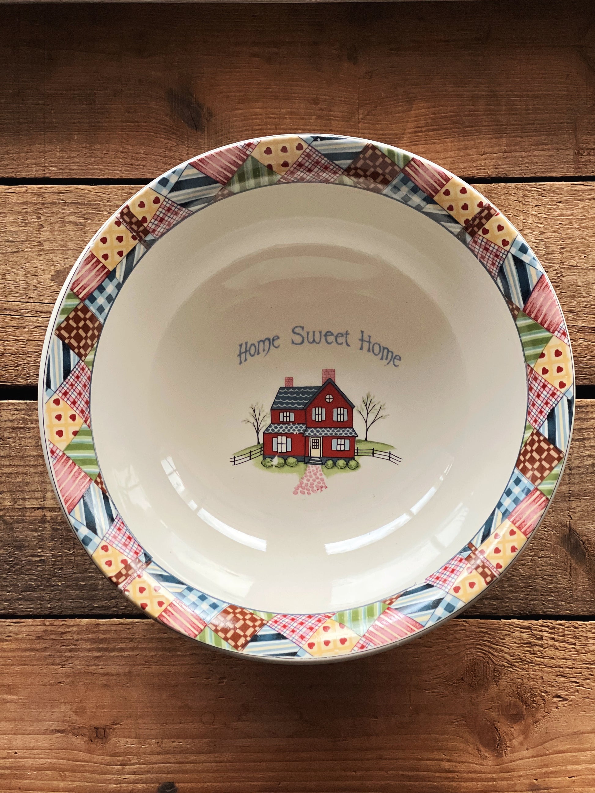 Decorative ceramic plate with colorful border and 'Home Sweet Home' text on a wooden surface