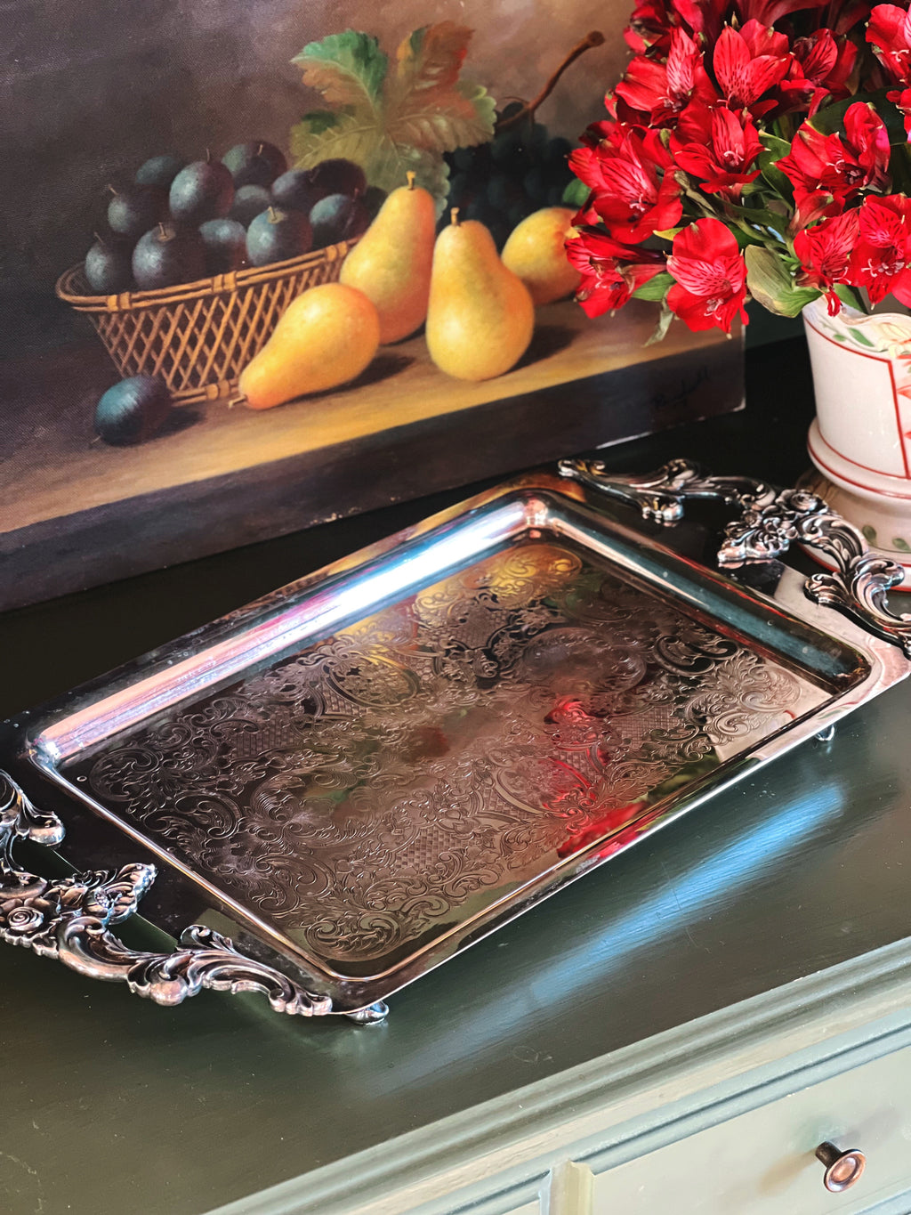 Decorative silver tray with fruit and flowers on a shelf