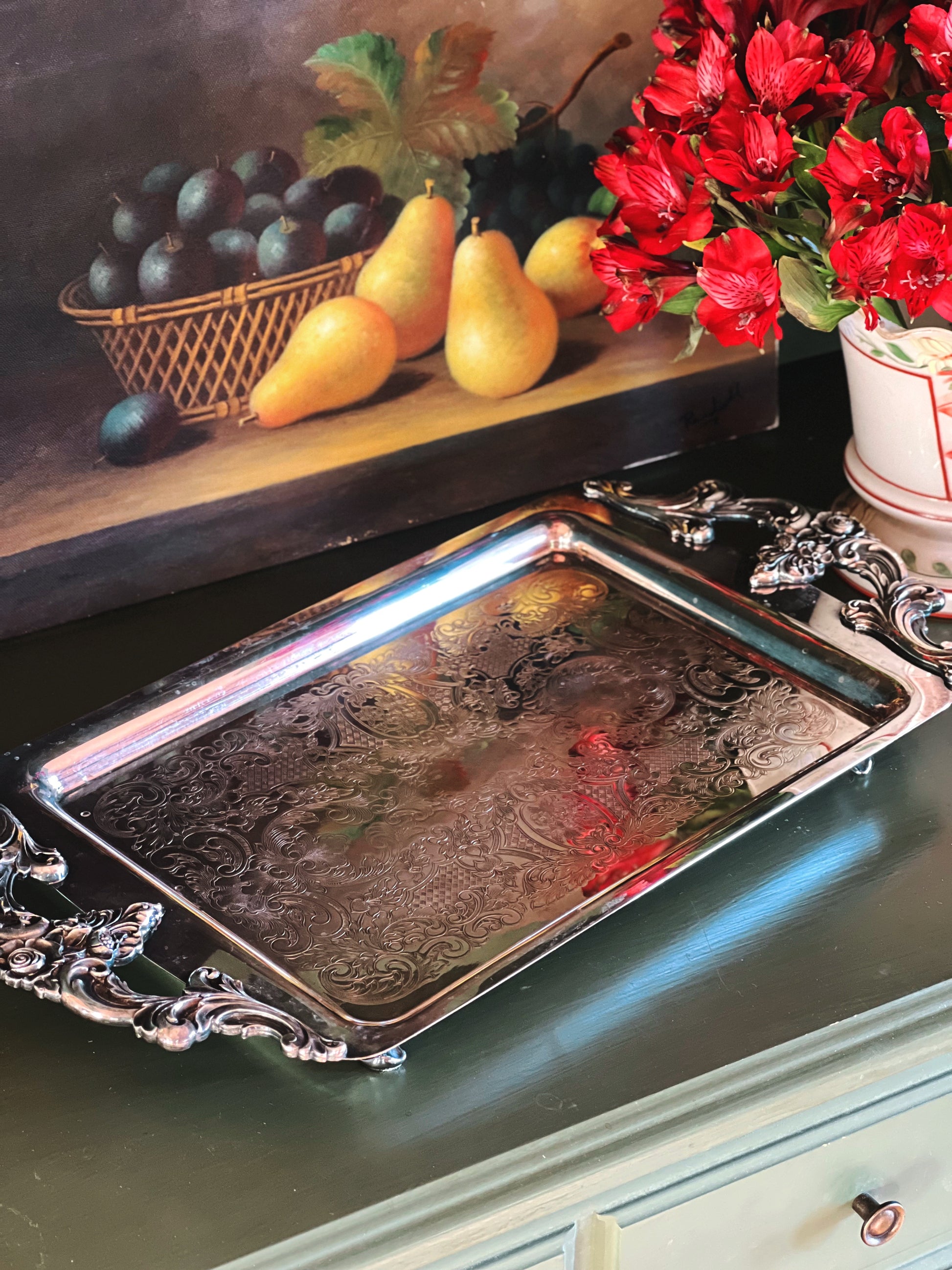 Decorative silver tray with fruit and flowers on a shelf