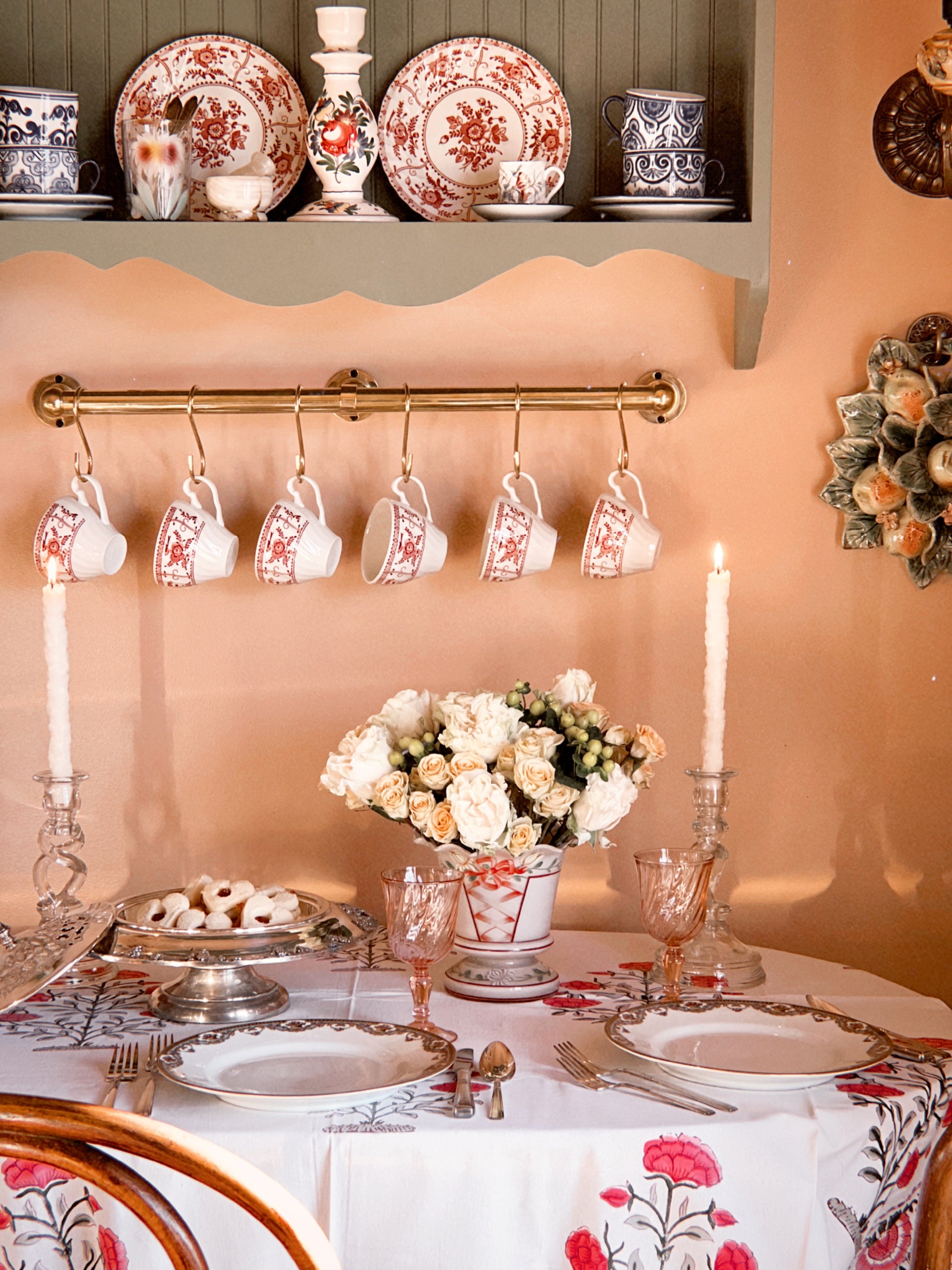 Decorative table setting with floral centerpiece, candles, and patterned tablecloth.