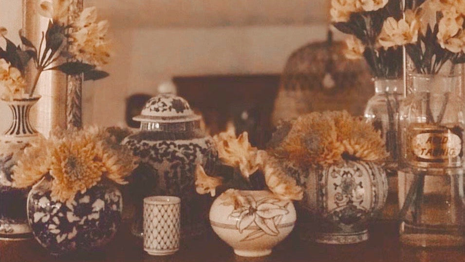 Decorative table setting with vases, candles, and flowers in a warm-toned room.