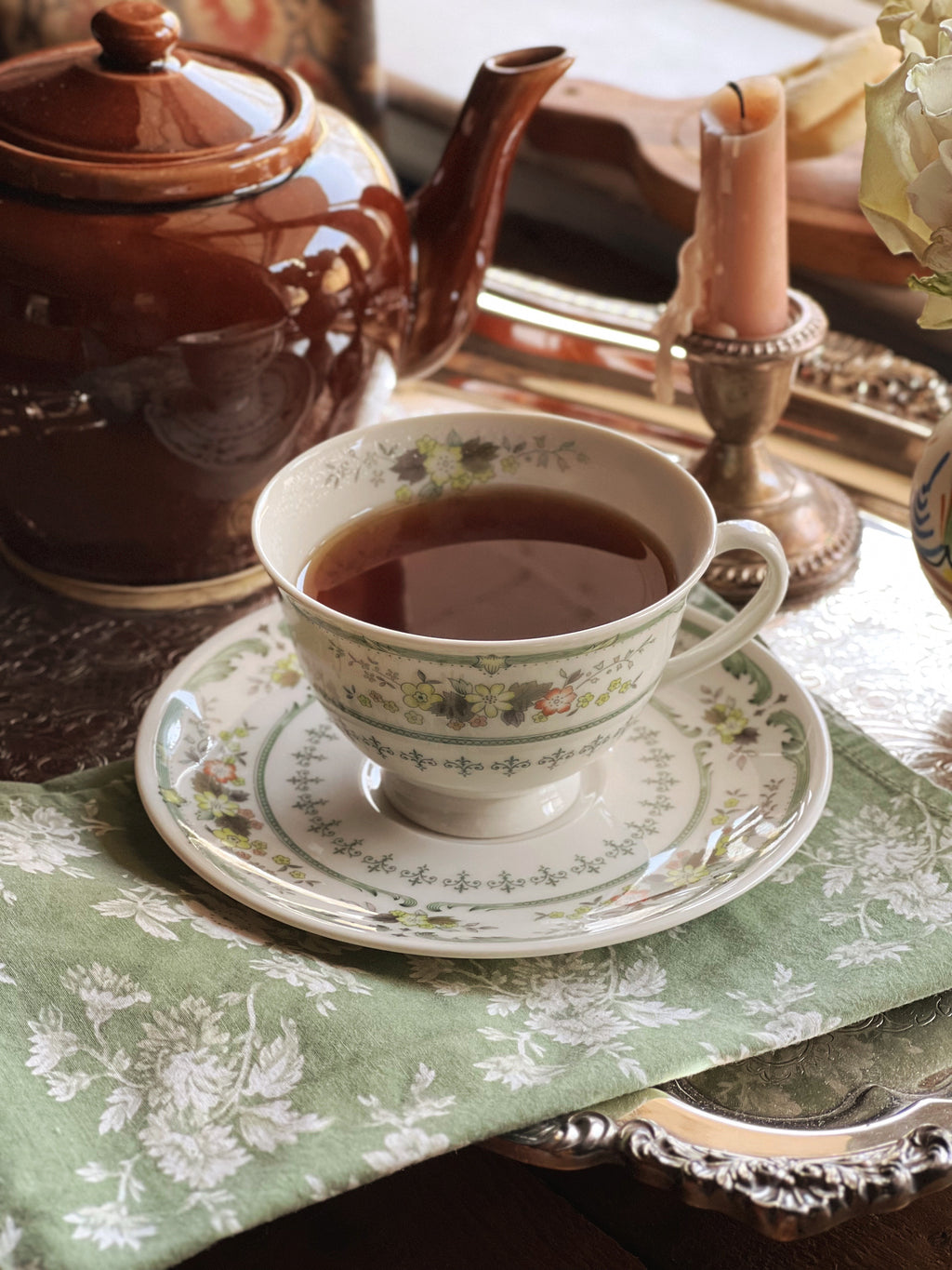 Vintage Royal Doulton Provencal flat tea cup and saucer beside a brown teapot on a green floral tablecloth