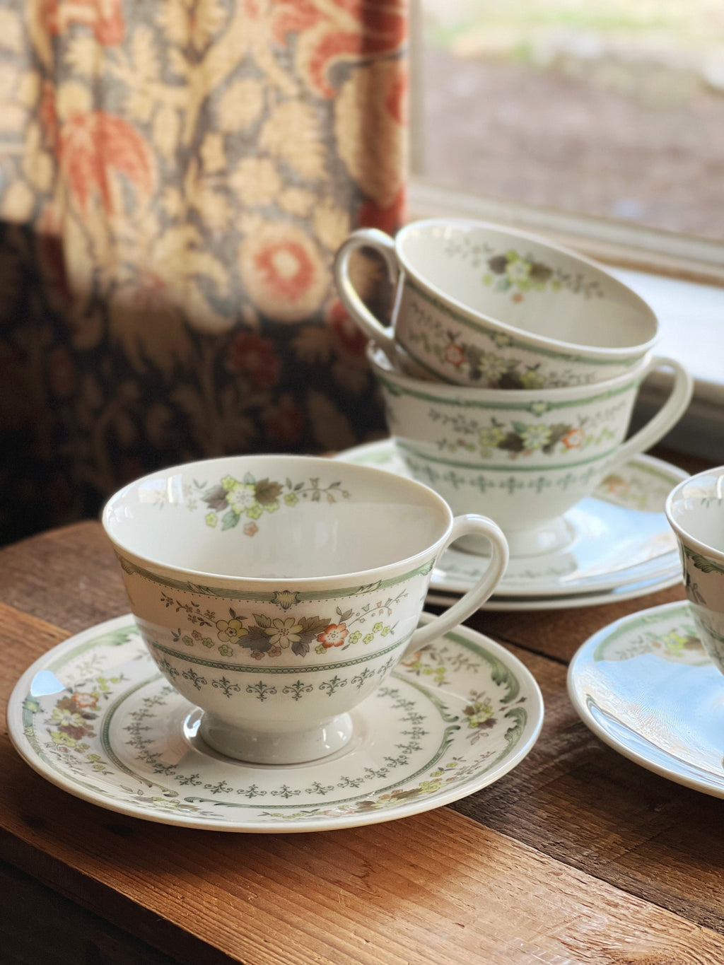 Set of floral teacups and saucers on a wooden table