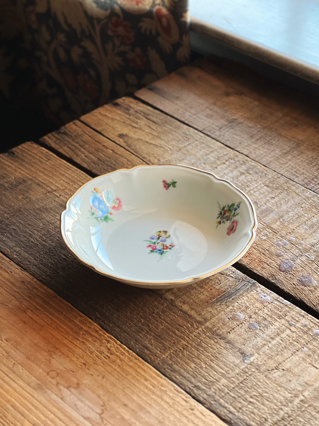 Small decorative ceramic bowl with floral patterns on a wooden surface