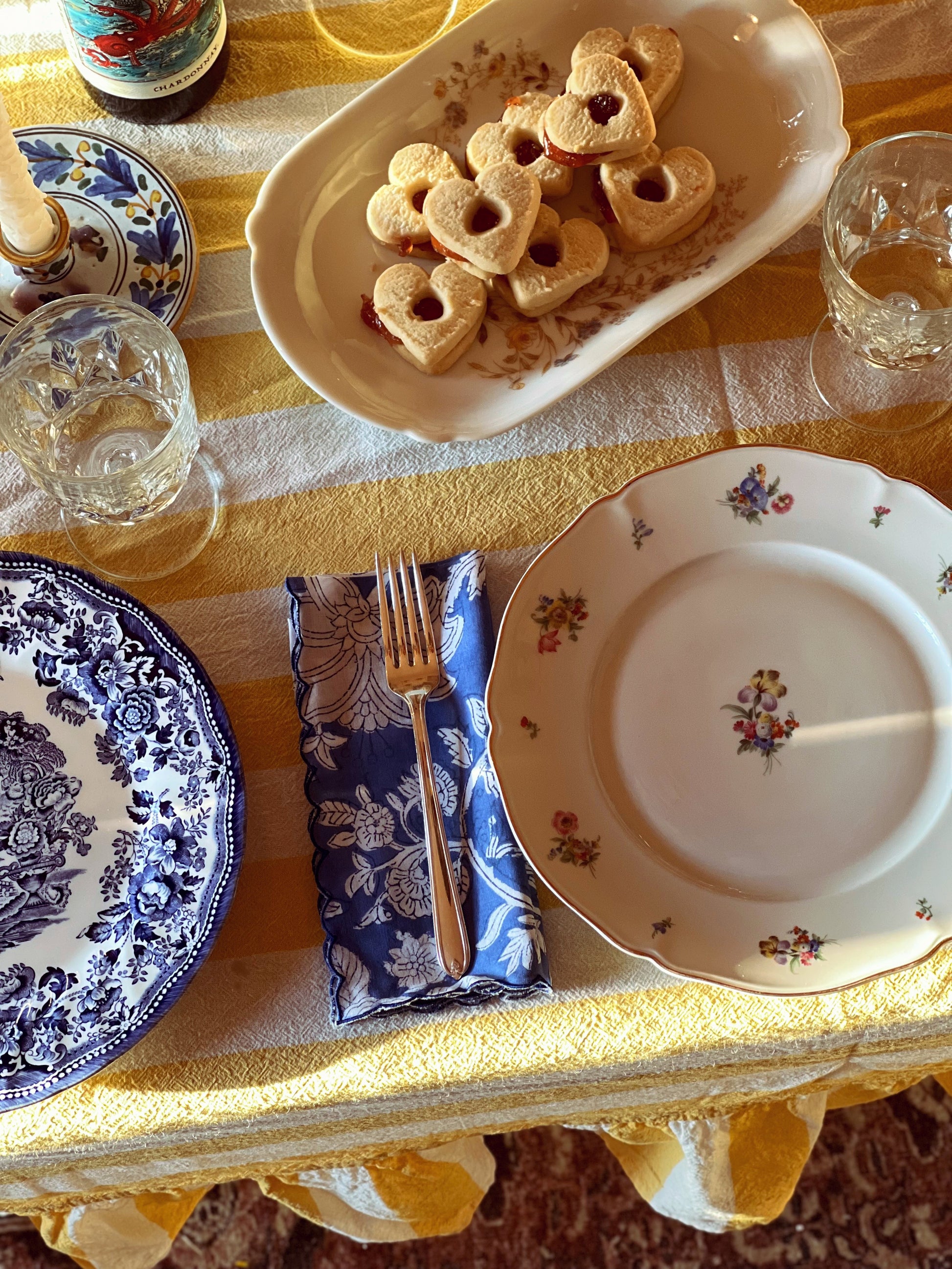 Dining table setting with plates, cutlery, and a plate of heart-shaped sandwiches.