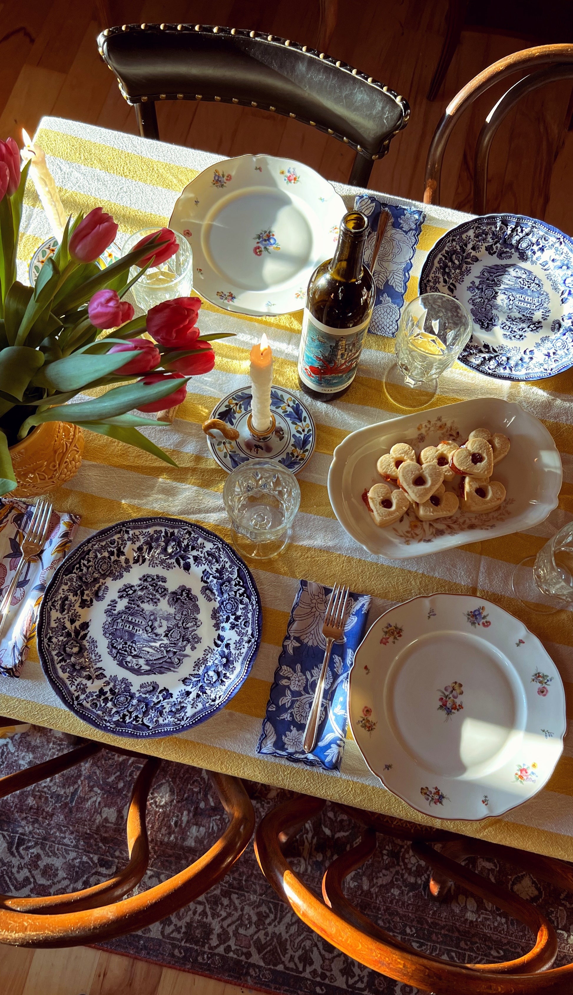 Dining table set with plates, glasses, and a bottle of beer on a checkered tablecloth.
