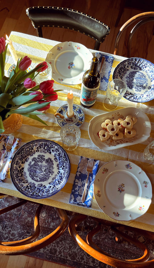 Dining table set with plates, glasses, and a bottle of beer on a checkered tablecloth.