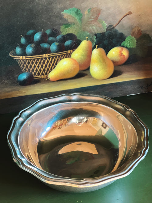 Still life painting of pears, plums, and grapes with a metallic bowl in the foreground.