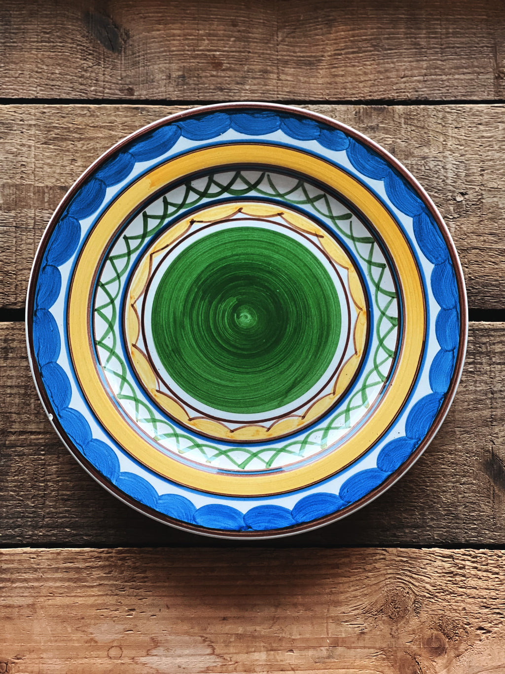 Decorative ceramic plate with blue and yellow patterns on a wooden surface