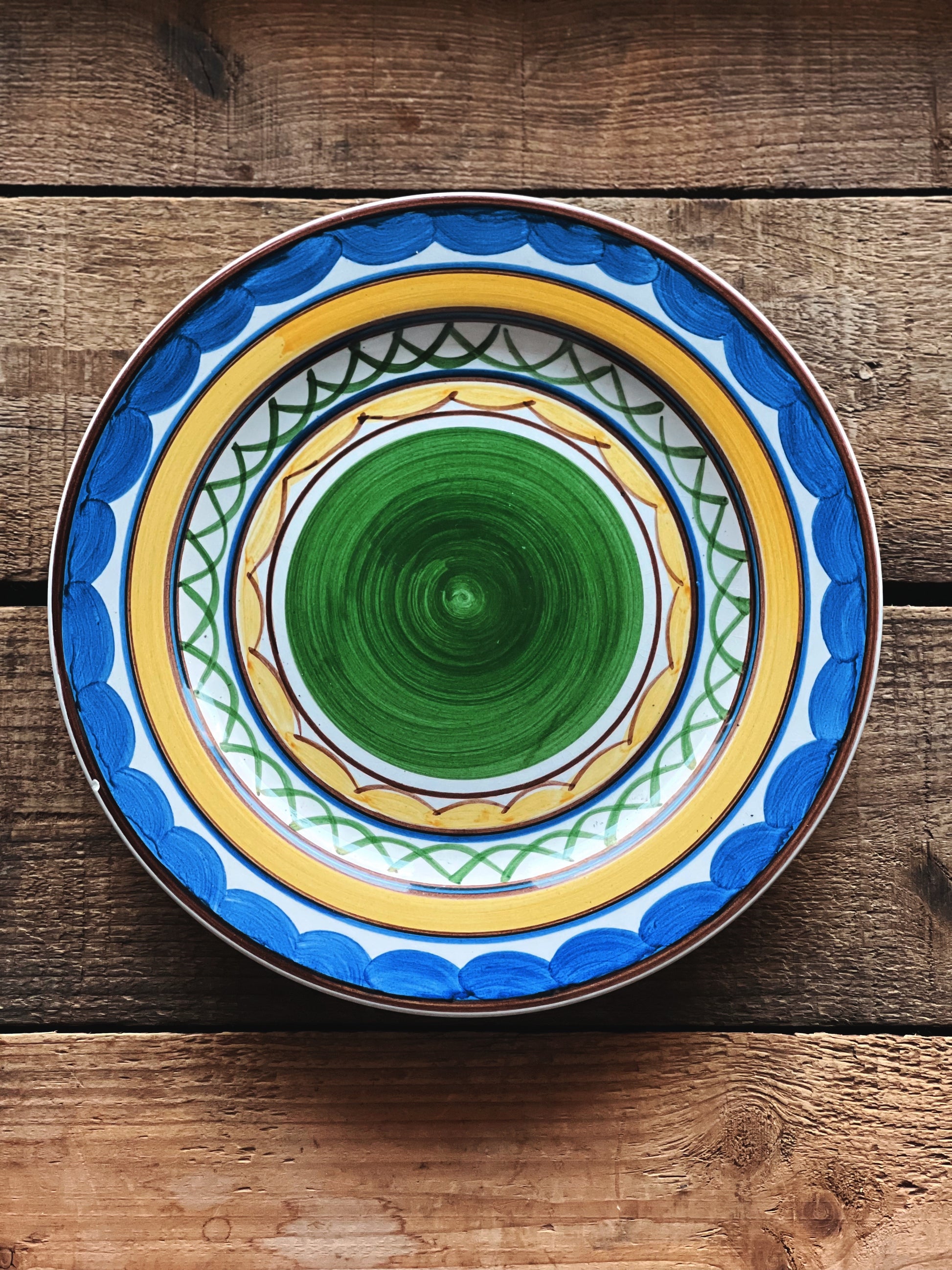 Decorative ceramic plate with blue and yellow patterns on a wooden surface