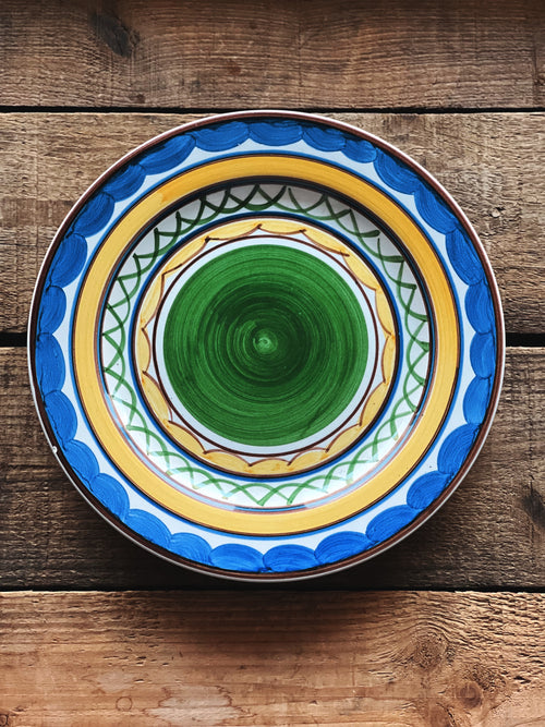 Decorative ceramic plate with blue and yellow patterns on a wooden surface