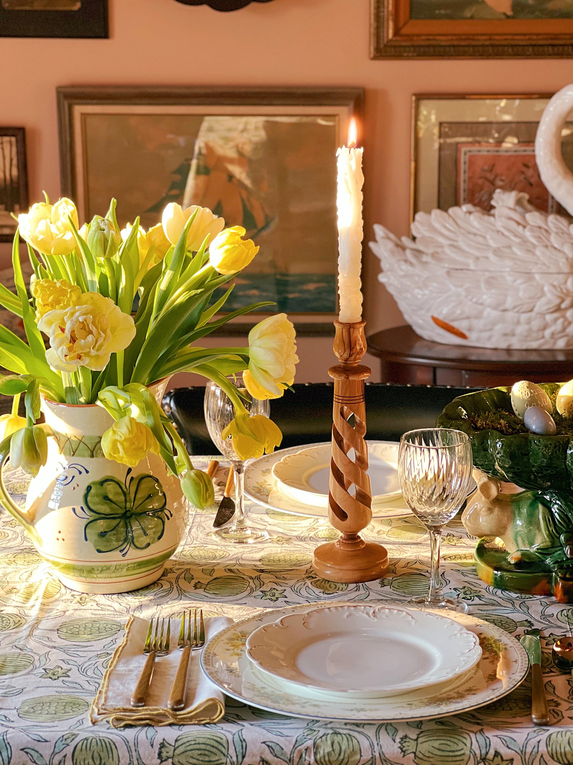 Decorative table setting with yellow tulips, candle, and vintage decor.
