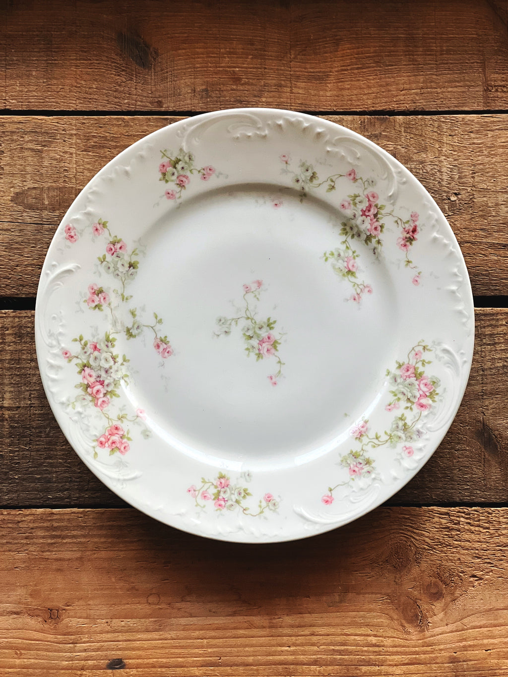 Decorative white plate with floral patterns on a wooden surface