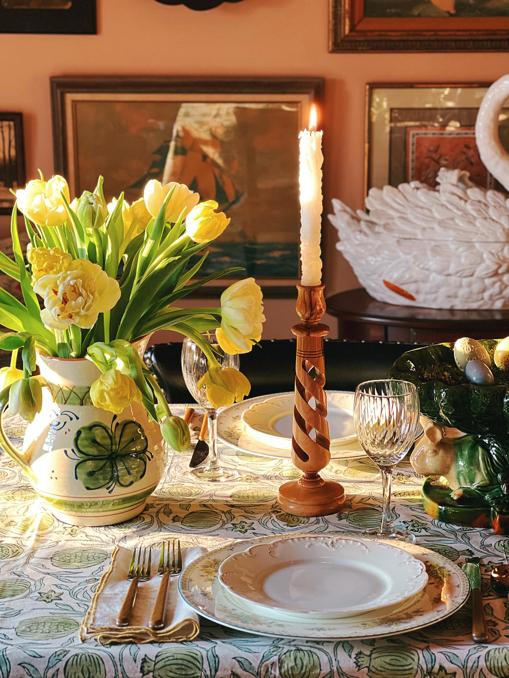 Easter table setting with yellow tulips, candles, and decorative eggs in a home setting.