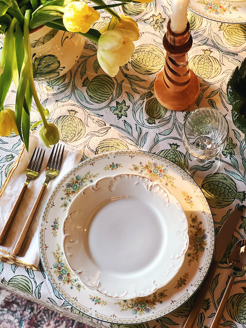 Elegant table setting with floral centerpiece, plates, and cutlery on a patterned tablecloth.