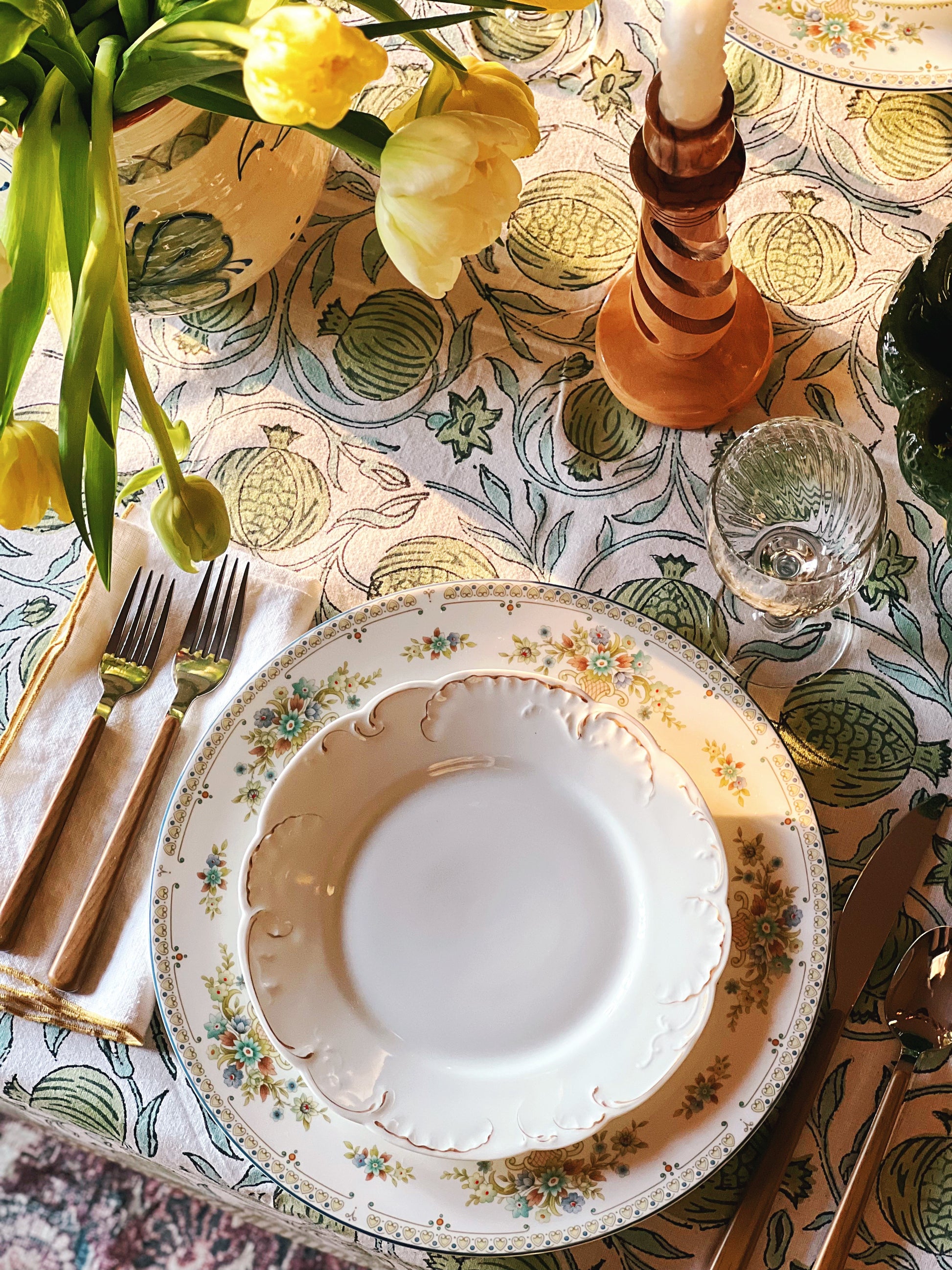Elegant table setting with floral centerpiece, plates, and cutlery on a patterned tablecloth.