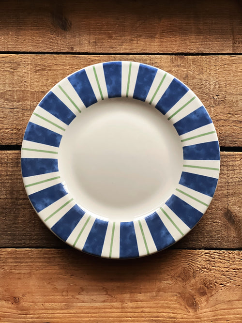 Ceramic plate with blue and green striped rim on a wooden surface