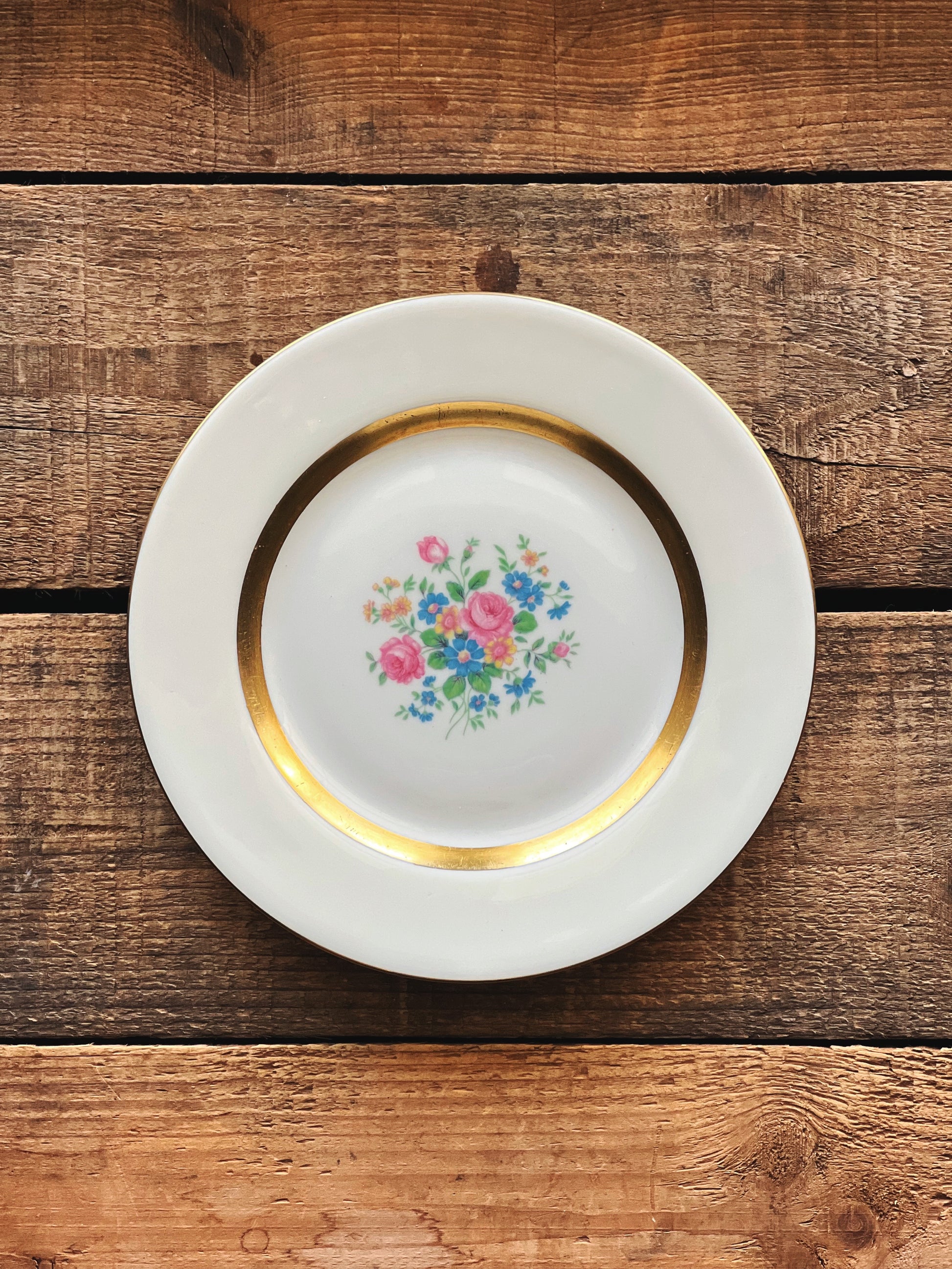 Decorative plate with floral design and gold rim on a wooden surface