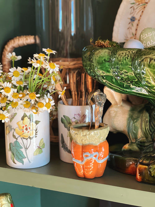 Decorative items including a vase with flowers, a green glass object, and a pumpkin-shaped container on a shelf.