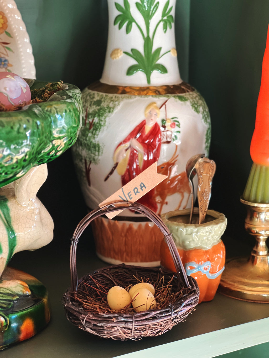 Decorative items including a vase with a painted figure, a small basket with eggs, and a green bowl on a dark surface.