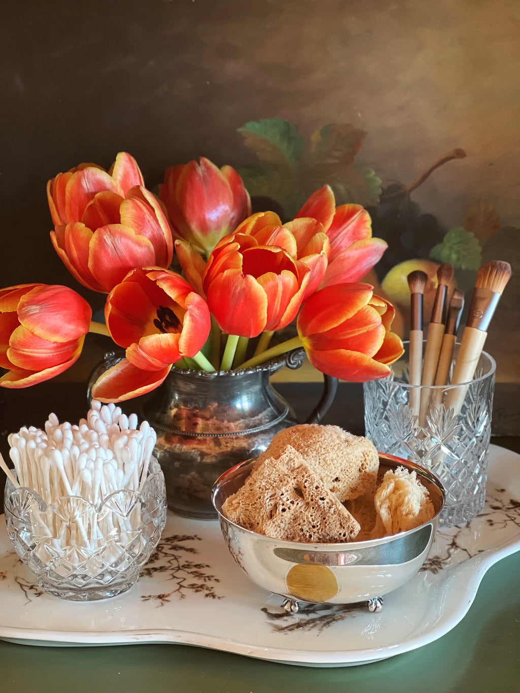 Antique floral transferware tray styled with orange tulips, crystal glassware, and pastries on a gathered spring table