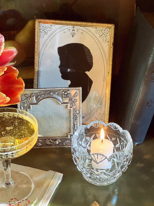 Decorative table setting with a silhouette portrait, candle, and glass of wine.