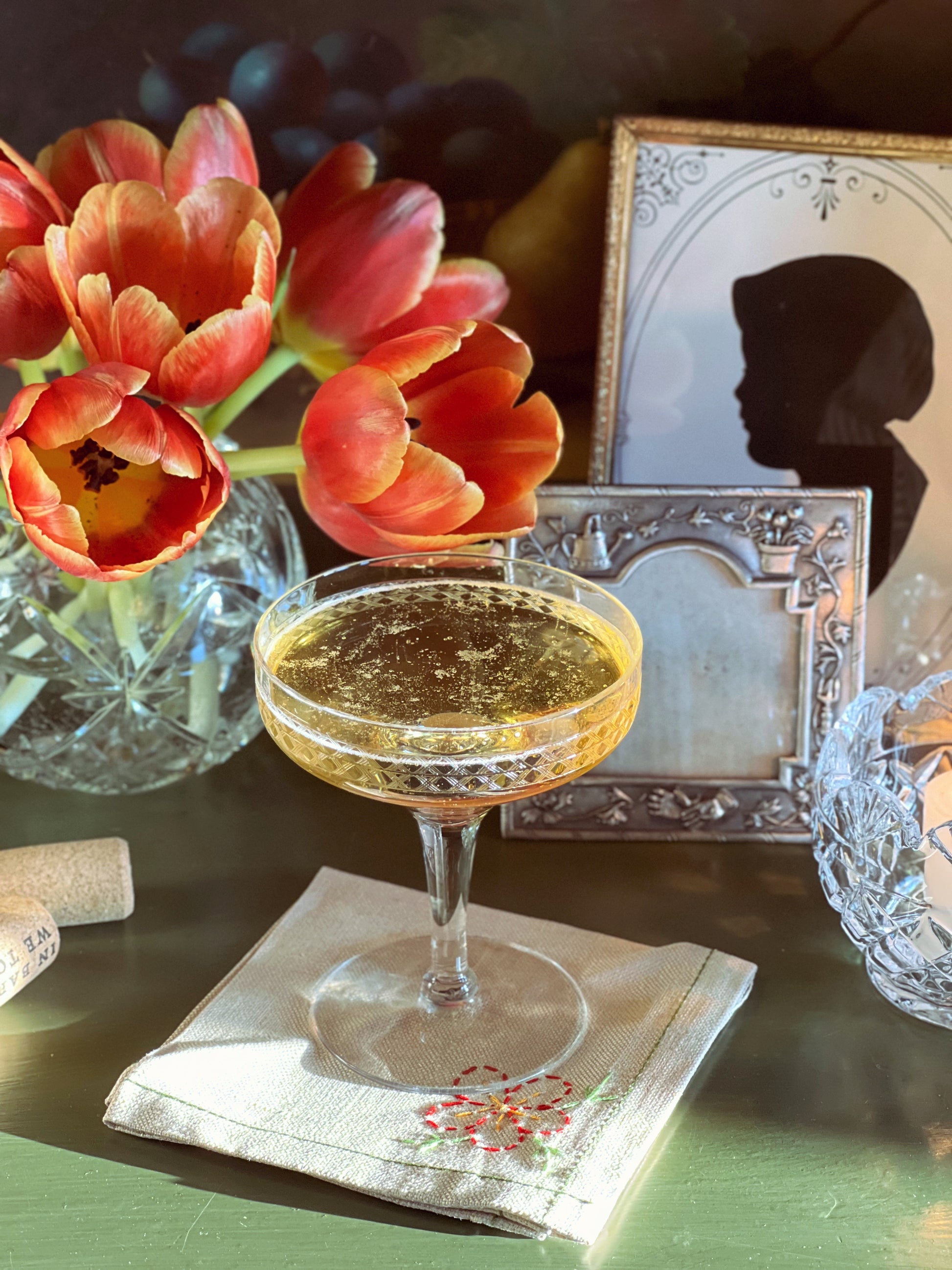 Cocktail glass with a floral arrangement and vintage photo in the background