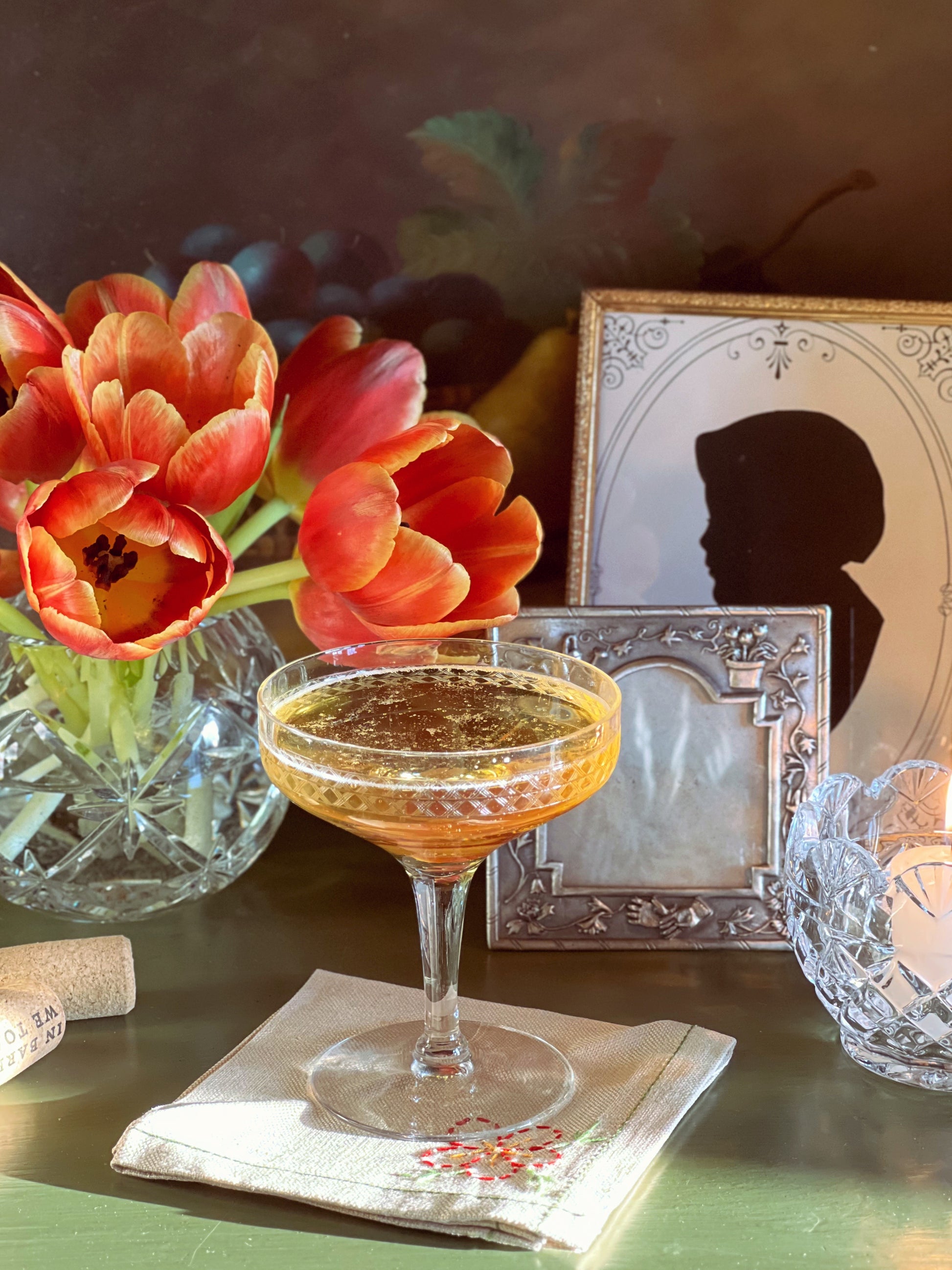 Cocktail glass with a floral arrangement and framed silhouette in the background