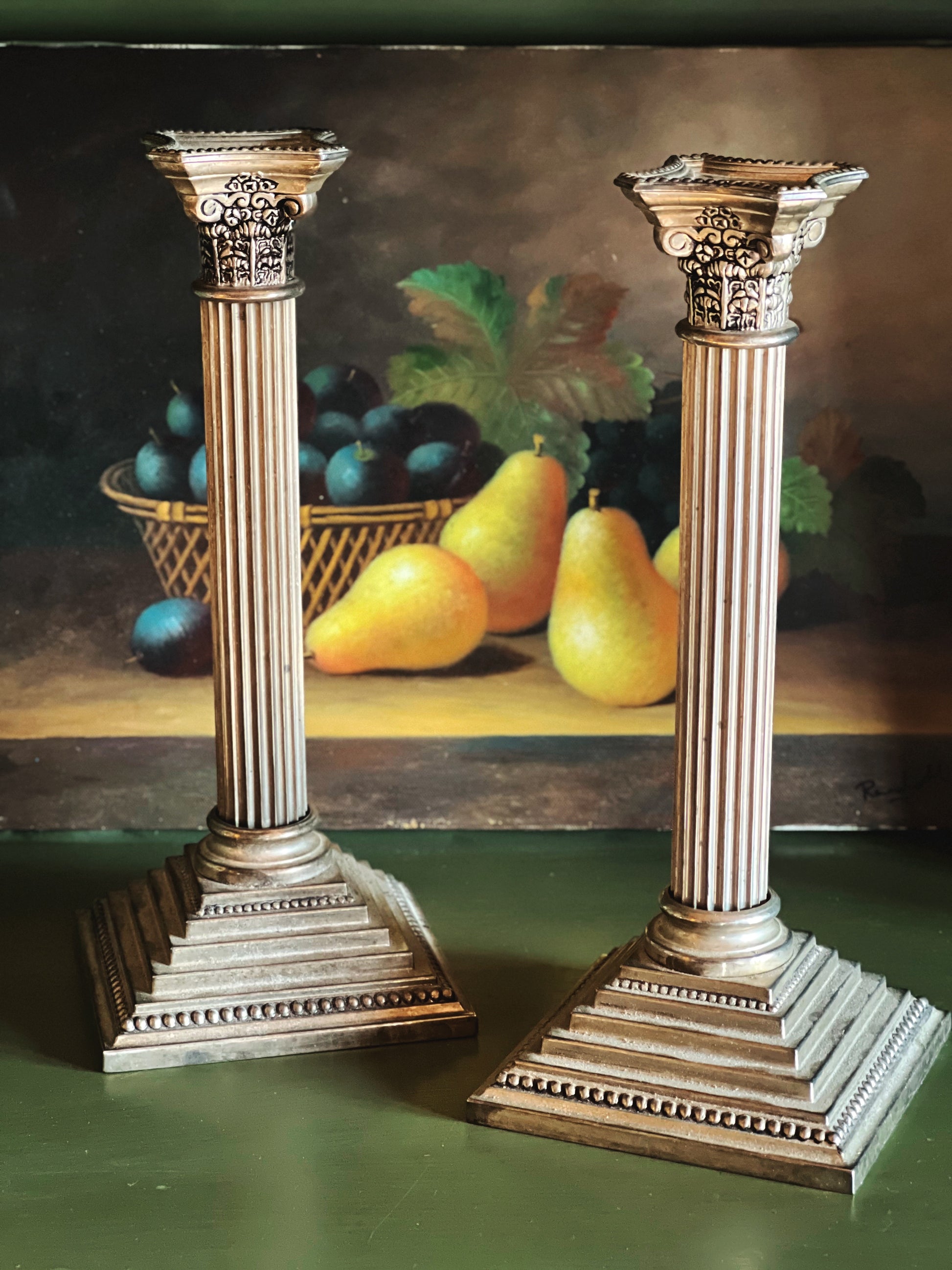 Decorative columns with a still life painting of fruit in the background