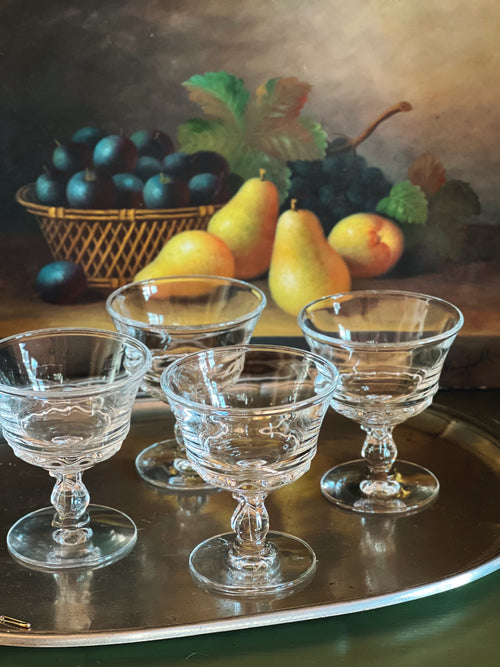 Still life painting of glass goblets and fruit on a reflective surface