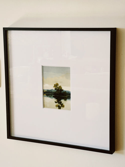 Framed photograph of a landscape with a tree on a lake.