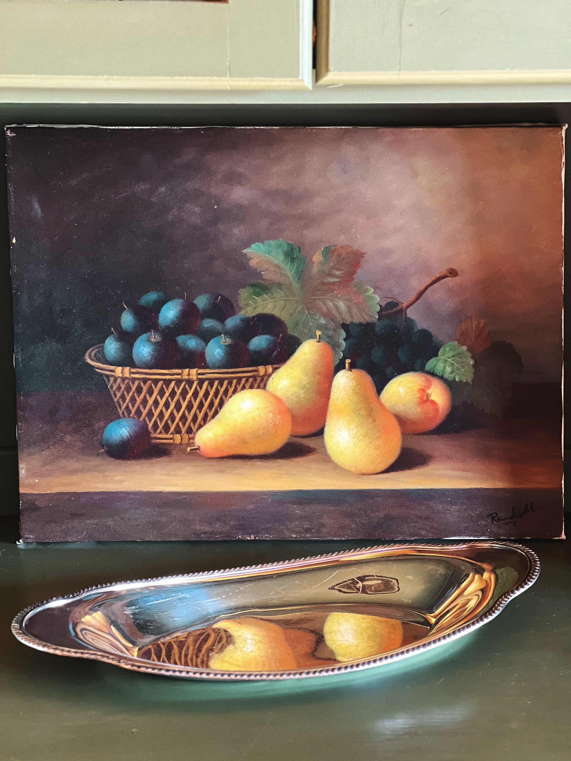 Framed still life painting of fruits on a table with a metal tray in front.