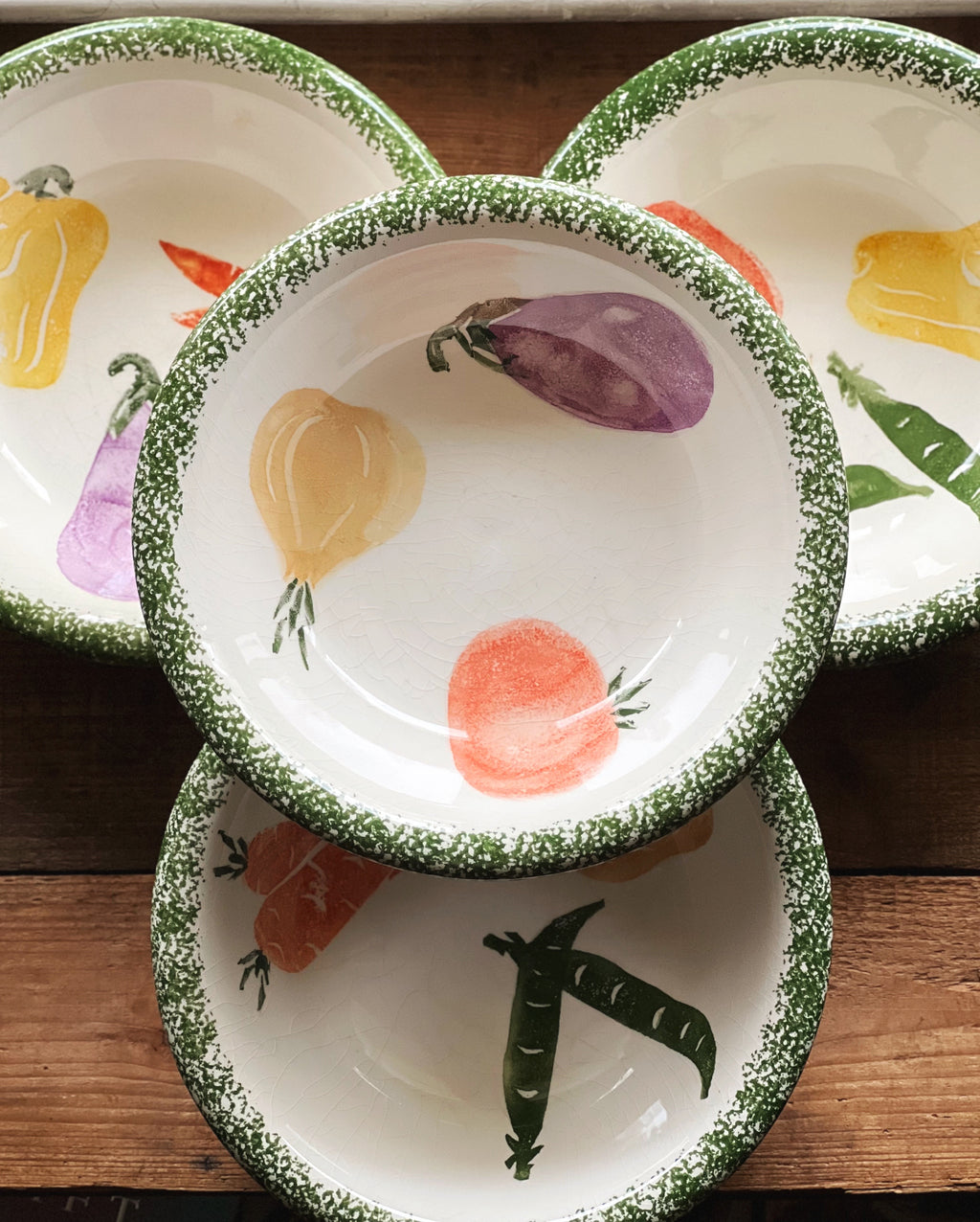 Set of ceramic bowls with vegetable illustrations on a wooden surface
